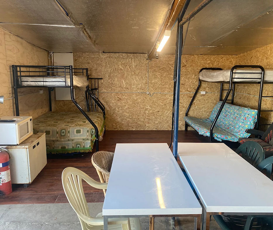 Rustic interior of Hilltop Cabin featuring bunk beds, seating area, and basic kitchen setup.