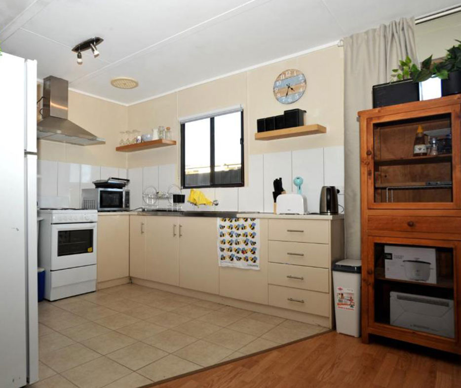 Fully equipped kitchen with stove, sink, and wooden cabinetry in Investigator Beach Breeze.